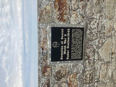 Black plaque on a stone wall describing a World War II radar station site.