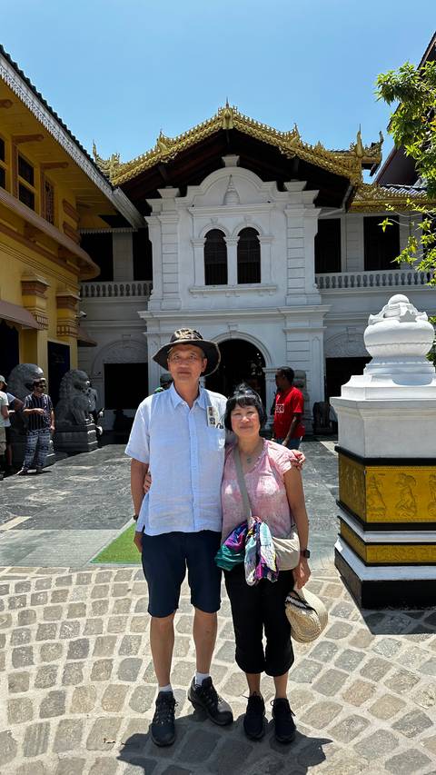 Travellers stand outside the entrance of a historic temple complex with carved stone lions.