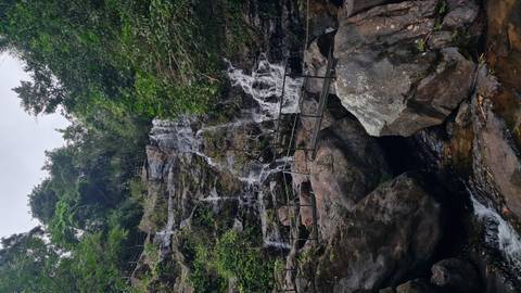 Multi-tiered waterfall cascades over rocks in a lush Vietnamese forest reserve.