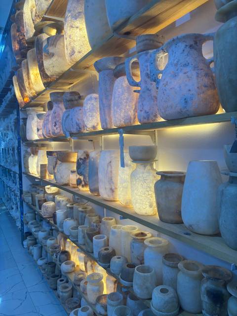Back-lit shelves displaying alabaster vases and candle holders in a souvenir shop