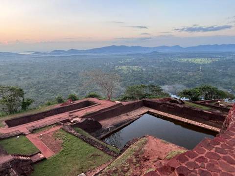 Dawn view from Sigiriya rock fortress over misty jungle and distant blue mountains.