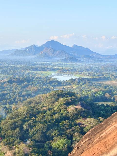 Hazy panoramic view of lakes, forests and distant mountains from a high vantage in Sri Lanka.