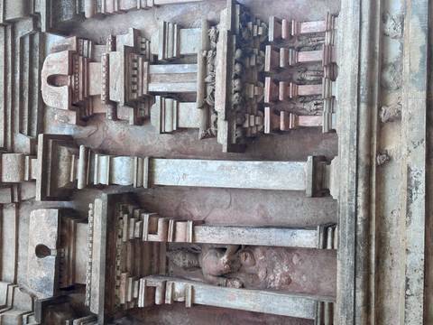 Detail of ancient stone reliefs and columns with faded pink patina on a Sri Lankan temple wall.