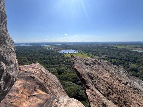Sweeping view from rocky cliff over lakes, wetlands and endless green plains under clear sky