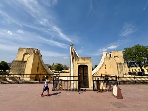 Young boy observing a massive yellow stone sundial at Jaipur's Jantar Mantar
