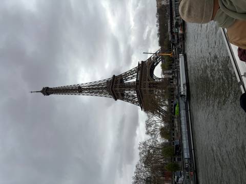 Eiffel Tower rising over the Seine River on an overcast day with boats moored along quay
