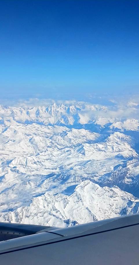 Aerial view of vast snow-covered mountain range seen from an airplane window.