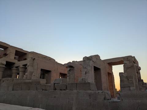 Ancient sandstone temple ruins silhouetted against a fading evening sky along the Nile.