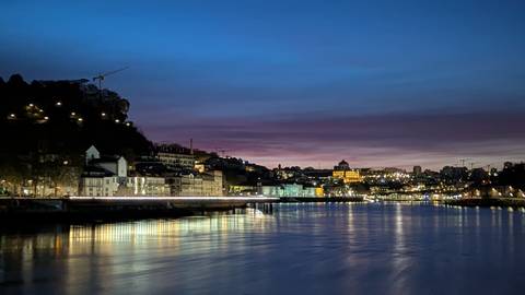 Evening panorama of Porto’s riverside lights reflecting on the Douro under a purple twilight sky.