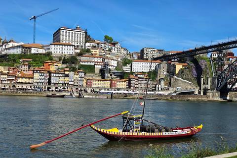 Colourful Porto riverside with rabelo boat on the Douro and the Dom Luís I Bridge in view.