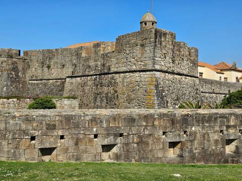 Massive granite ramparts of an old fort set against a vibrant blue sky.