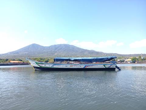 Wooden cargo boat moored on calm water with a volcanic mountain backdrop