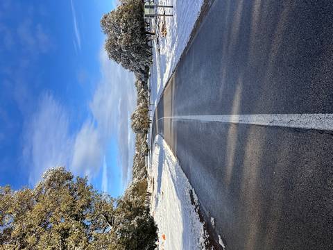 Straight snow-lined road disappearing into rolling white landscape beneath a blue sky