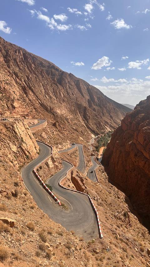 Winding mountain road snaking through steep red rock walls of Dades Gorge