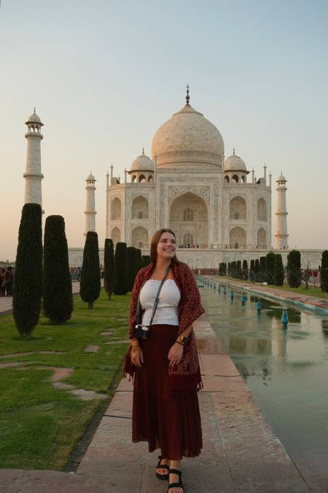 Smiling traveler posing in front of the Taj Mahal’s marble façade at dawn.
