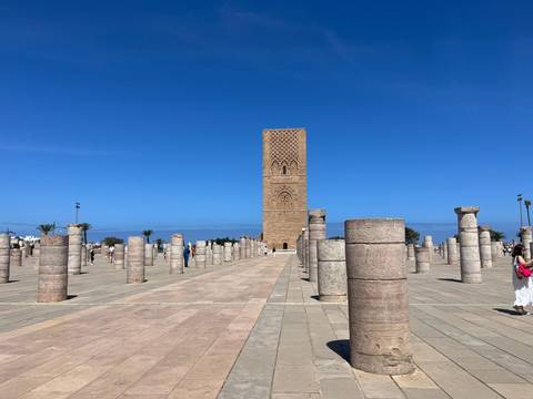 The Hassan Tower rises among rows of ancient stone columns on a bright day.