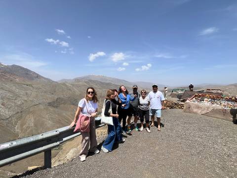 Group of travellers posing at a high mountain pass viewpoint under clear blue skies