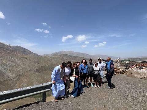 Travel group smiling with a local guide at a mountain lookout on a clear day