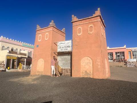 Traveller standing at the historic Tizi n'Tichka pass gate with altitude sign in High Atlas