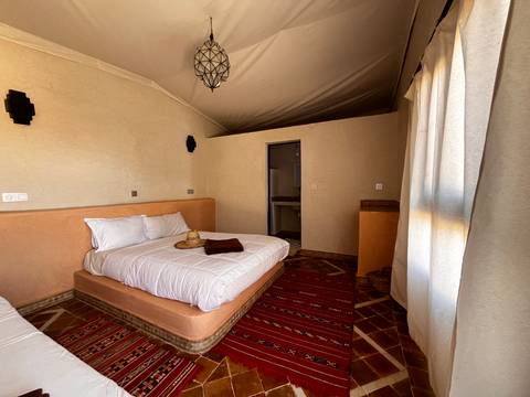 Bright desert lodge room with low twin beds, woven rugs and soft light
