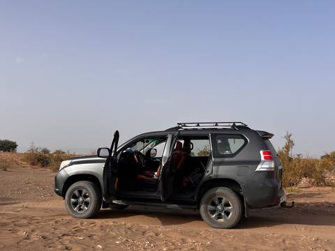 4x4 vehicle with doors open parked on dusty desert plain under hazy sky
