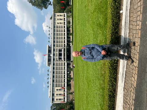 Traveler posing on the lawn before the façade of the Reunification Palace under a blue sky.