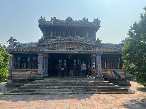 Small group exploring the front steps of an elaborately carved temple hall.