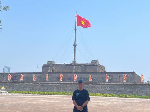 Traveler standing before the massive flag tower of the Hue Citadel with Vietnam flag flying.