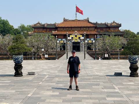 Visitor centered in front of the richly decorated Thai Hoa Palace courtyard.