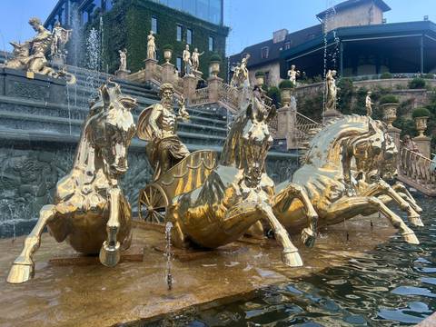 Gleaming golden statue of a charioteer and four horses in a fountain at Ba Na Hills.