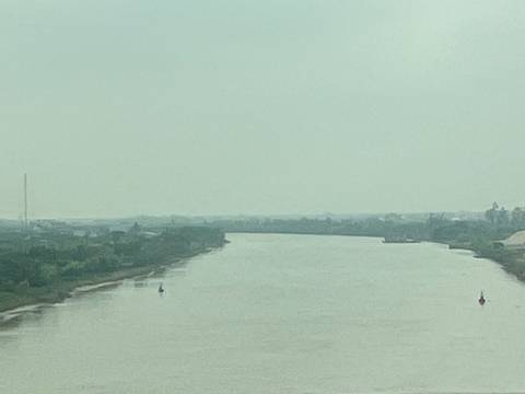 Overcast view of a wide muddy river bending through flat countryside.