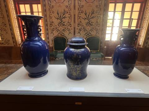 Display case with three deep blue porcelain vases in a palace museum.