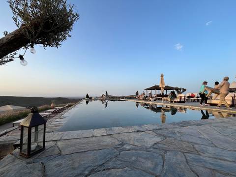 Infinity pool reflecting sky at a desert camp during golden hour with guests relaxing around the terrace