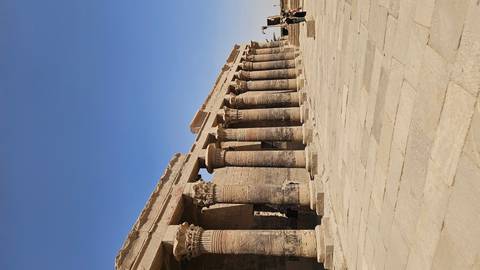 Row of ornate stone columns and reliefs lines a sun-drenched courtyard at Kom Ombo Temple.