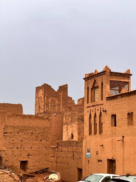 Detail of historic adobe kasbah walls with decorative windows and crumbling towers under a clear evening sky.