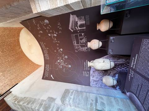 Museum exhibit with map board and ancient pottery jars displayed under vaulted brick ceiling.