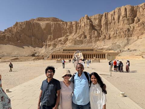 Family group stands before the grand terraced Temple of Hatshepsut built into limestone cliffs.
