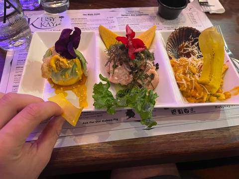 Colorful Peruvian tasting platter featuring ceviche, avocado, plantain chips and edible flowers.