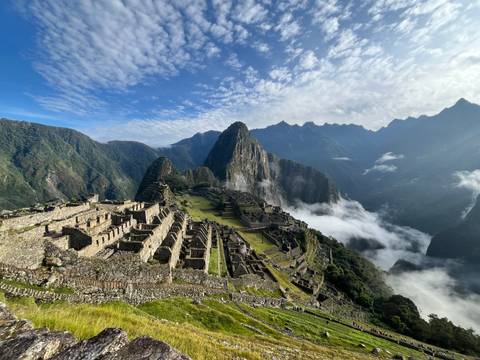 Iconic aerial view of Machu Picchu’s stone terraces rising above clouds and Andean peaks.