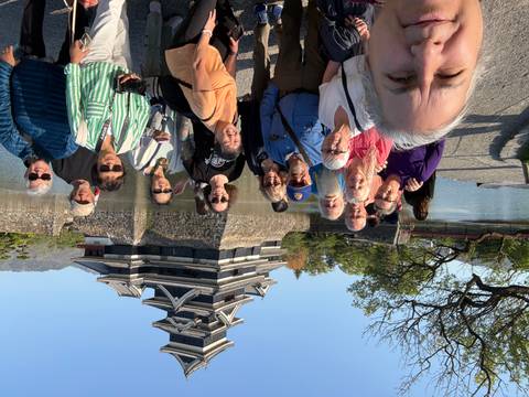 Excited tour group taking a selfie in front of a traditional Japanese castle surrounded by a moat.