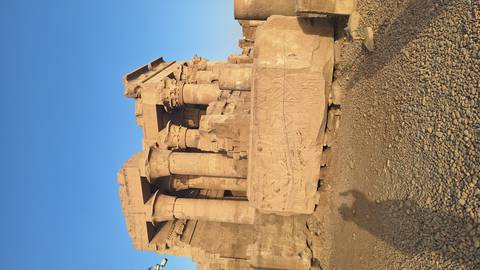Ruins of Kom Ombo temple columns and carvings under clear evening sky with long shadows.