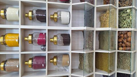 Shelves of colourful spices and herbs neatly arranged in glass jars and bins at a market shop.