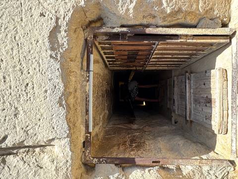 Visitor crouching to enter a narrow ancient stone passageway inside a pyramid.