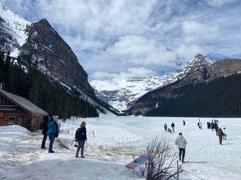 Visitors exploring the frozen surface of Lake Louise surrounded by dramatic snowy peaks