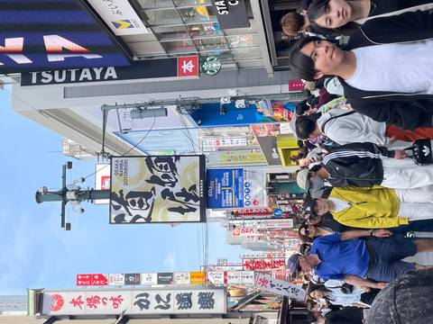 Bustling Dotonbori street in Osaka packed with shoppers beneath colourful neon and kanji signs.