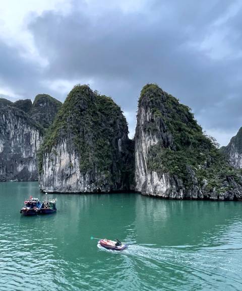Twin sheer limestone islands stand in turquoise water beneath a moody sky.