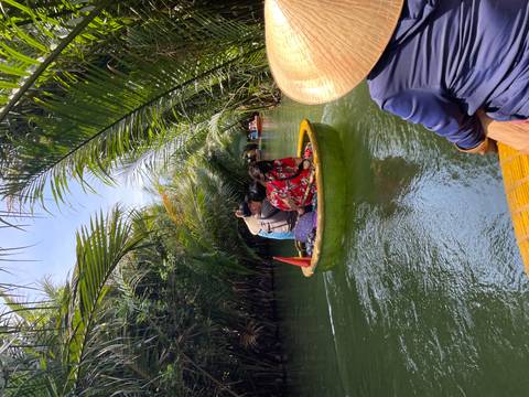 Round bamboo boat glides through a tunnel of nipa palms on calm green water.
