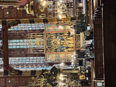 Ornate gilded altarpiece and vivid stained-glass windows inside a grand gothic basilica.