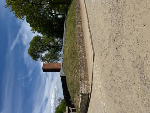 Low grassy mound with a solitary brick chimney against a blue sky with wispy clouds.