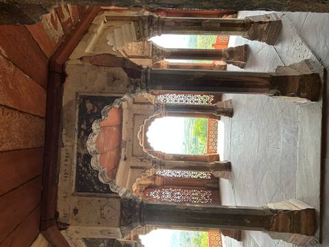 Interior pavilion with scalloped arches at an Indian fort offering views over green countryside.